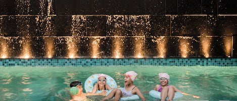 Una piscina con fuente y suelo de baldosas.