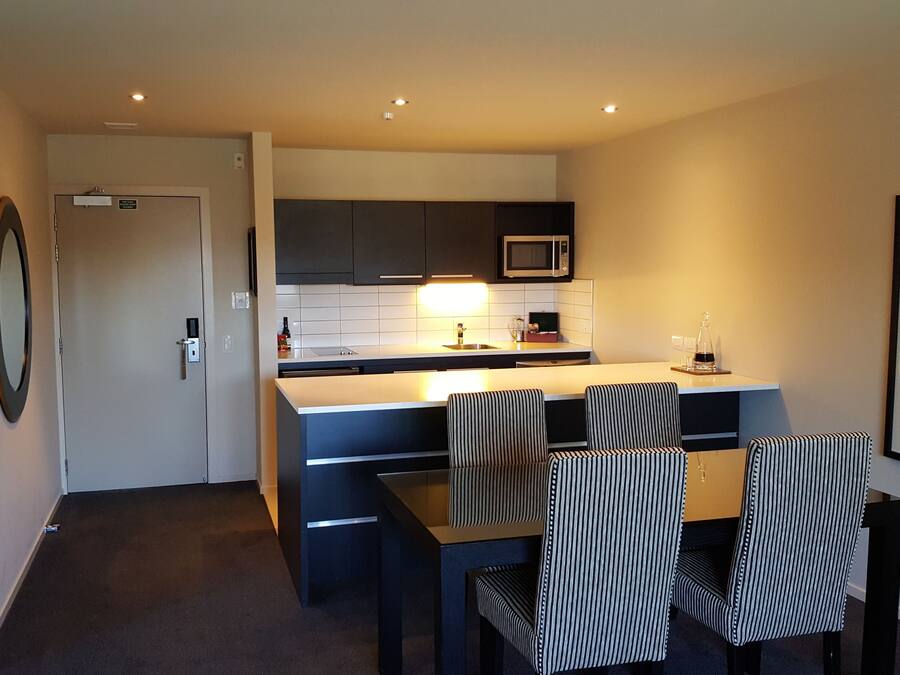 A modern kitchen with a microwave, sink, and a dining area with striped chairs.