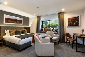 A hotel room with a bed, a sofa, a chair, a table, and two windows. - Carnmore Chateau Marlborough (Blenheim)