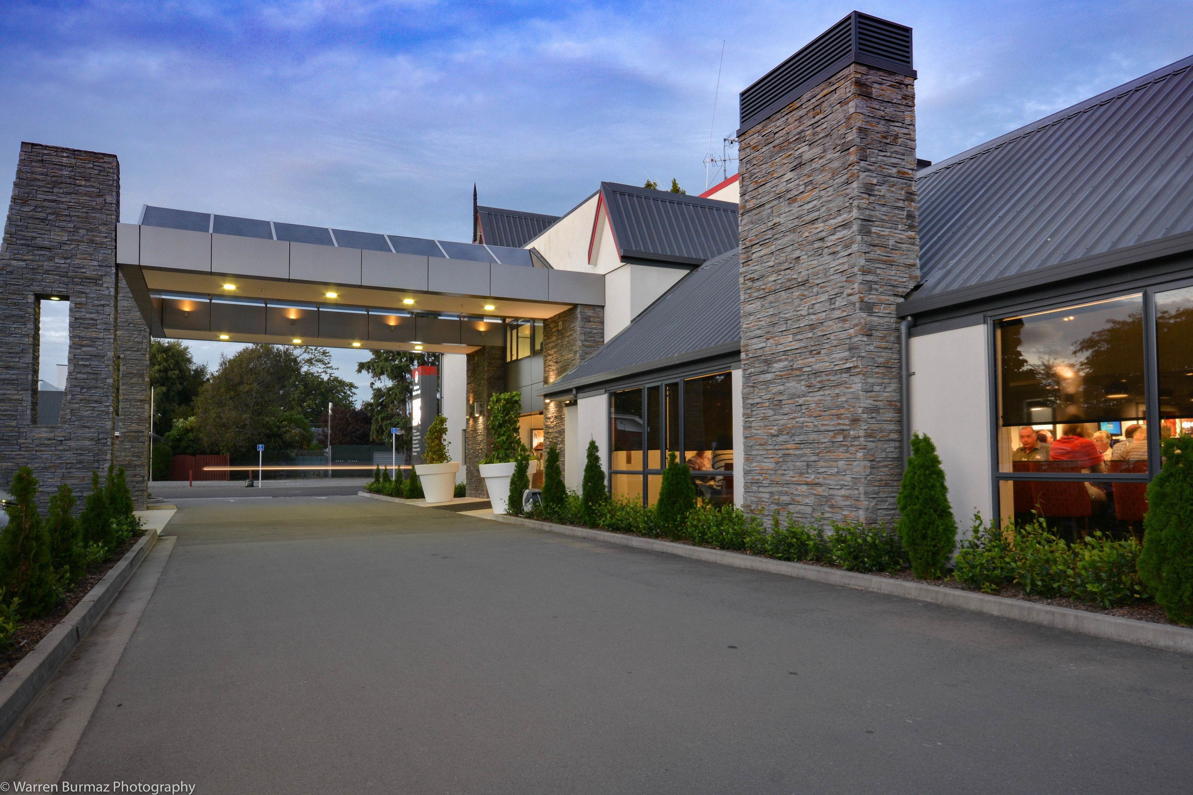 A modern building with a stone facade, large windows, and a covered entrance area.