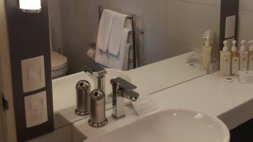A modern bathroom with a large mirror, a white sink, and a towel rack.
