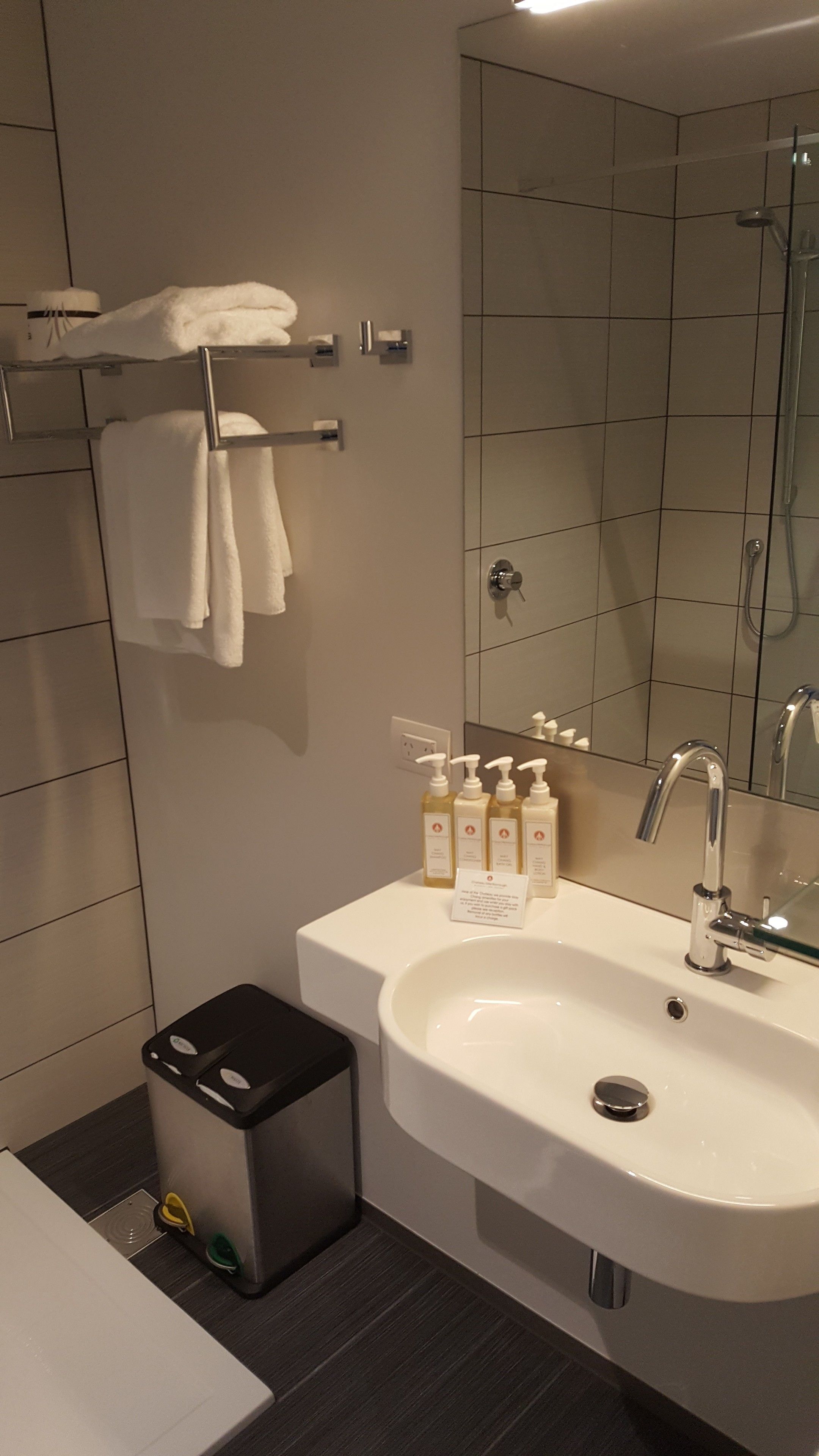 Ein modernes Badezimmer mit einem großen Waschbecken, einem Spiegel und einem Handtuchhalter.