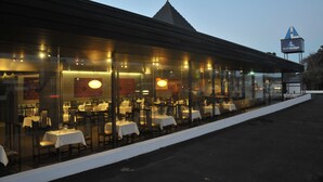 Zona pranzo all'aperto con tavoli e sedie, un tetto coperto e un cartello con la scritta 'autolodge'.