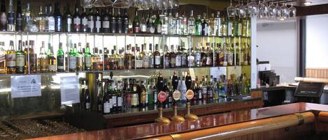 A bar with shelves of liquor bottles and a beer tap.