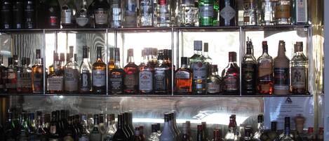 A bar with multiple shelves of various liquor bottles.