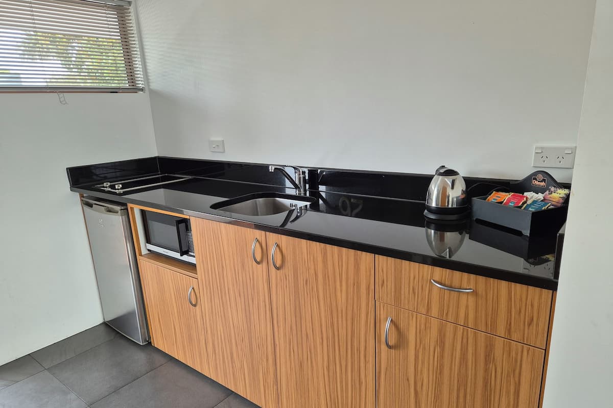 A compact kitchen with a black countertop, stainless steel appliances, and wooden cabinets.