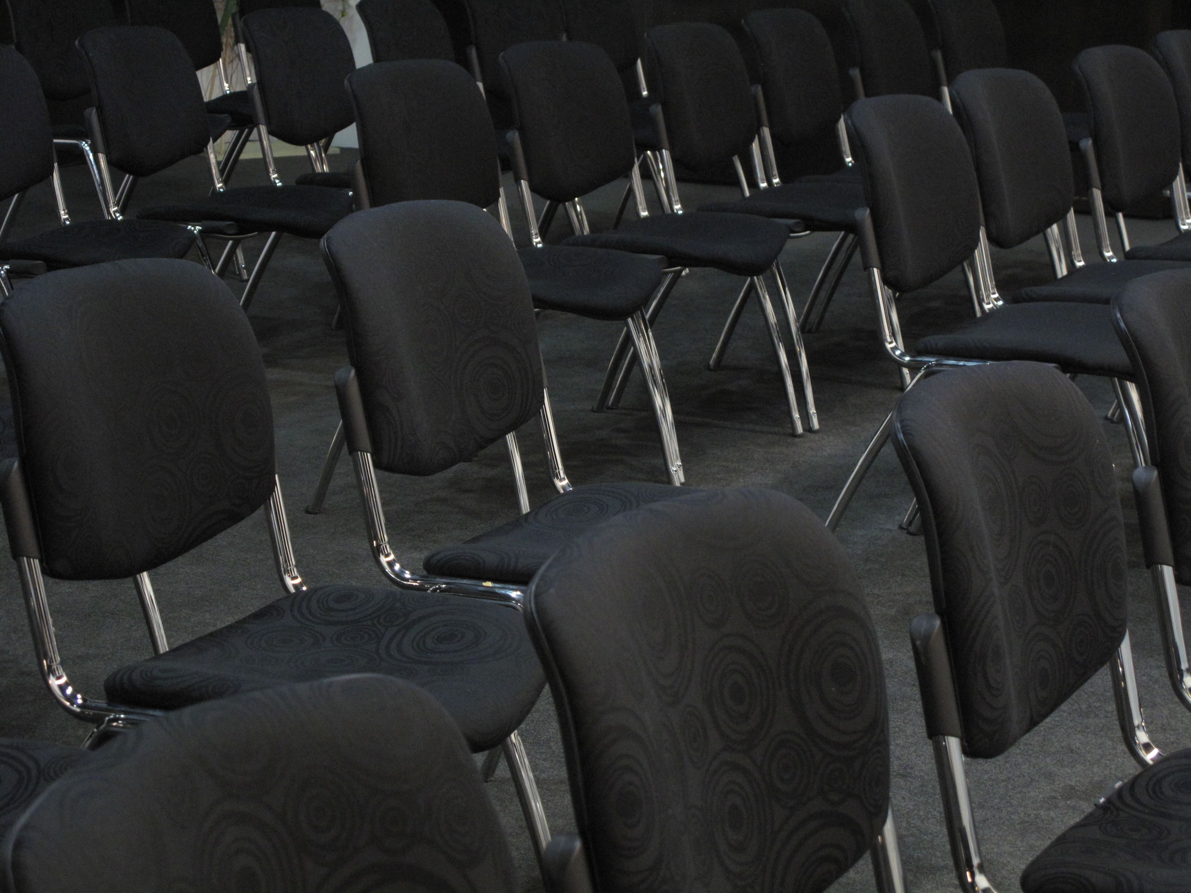 Filas de sillas negras con un diseño circular, dispuestas en un espacio para eventos.