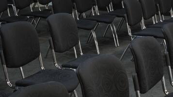 Filas de sillas negras con un diseño circular, dispuestas en un espacio para eventos.