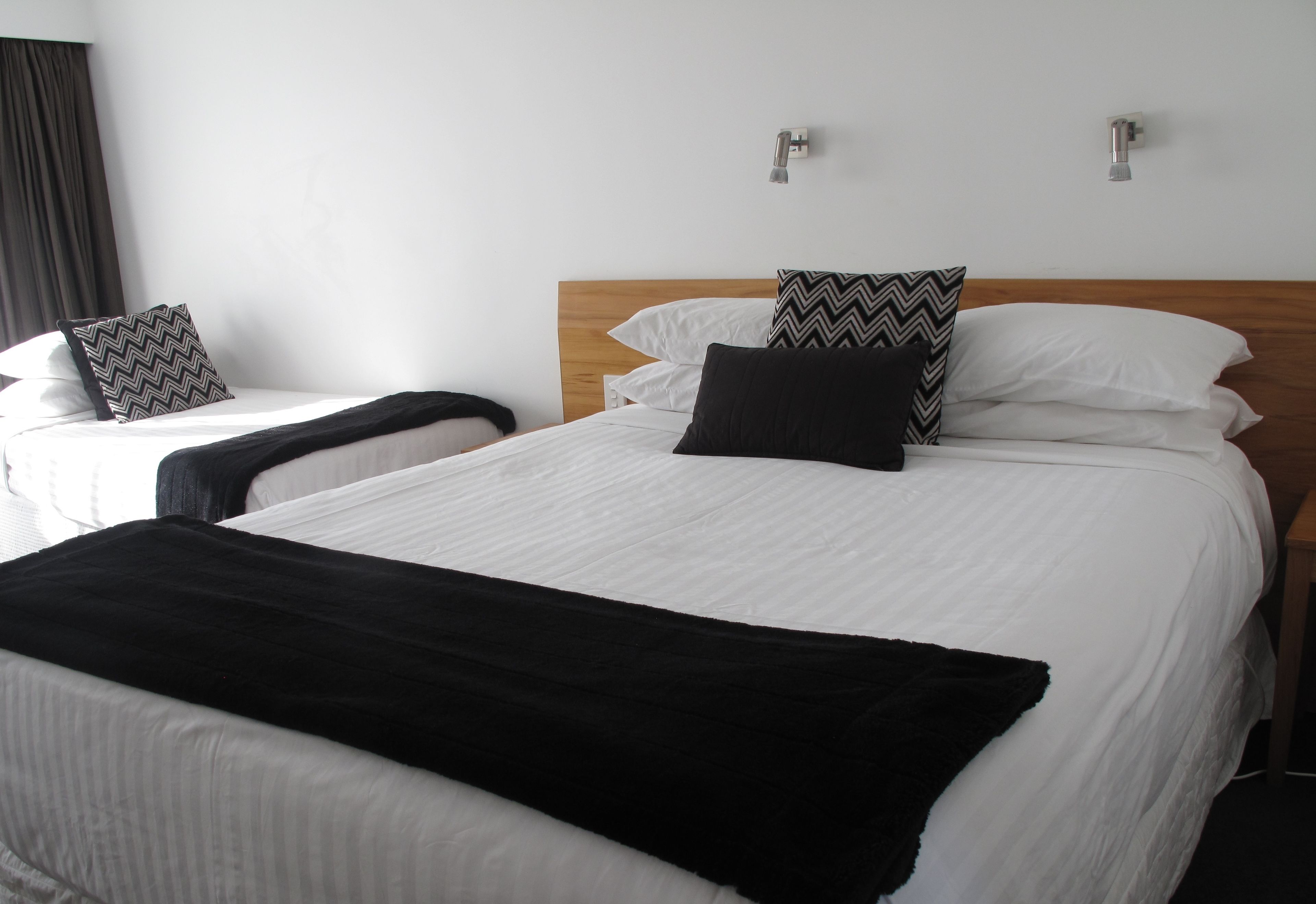 Habitació d'hotel amb dos llits, cada un amb roba de llit blanca i naxes estampades en blanc i negre.