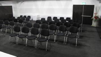 A conference room with rows of black chairs and a white table.