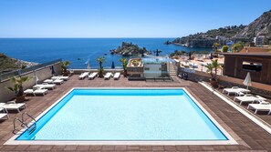 Una piscina al aire libre, sombrillas, sillones reclinables de piscina