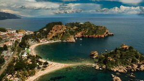 Un pueblo costero con playa, afloramientos rocosos y edificios a lo largo de la costa.