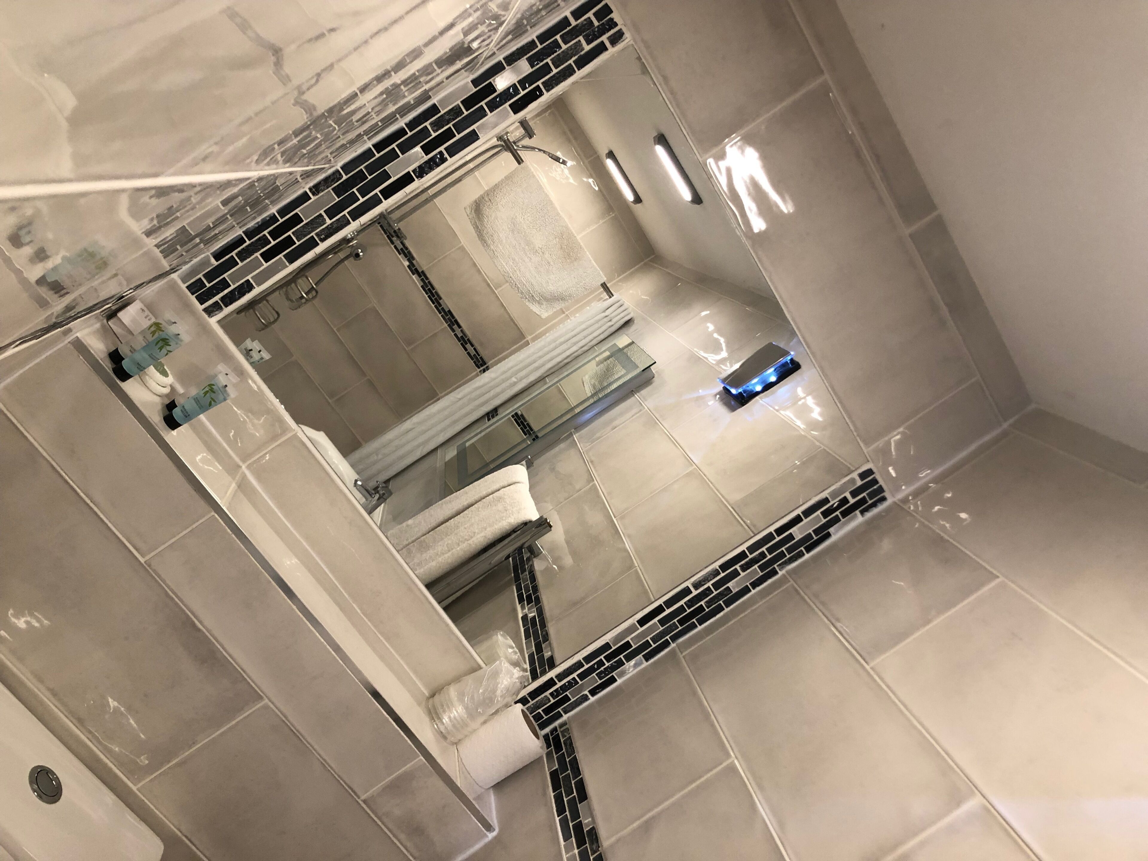 A bathroom with a large mirror, a shower, and a toilet.