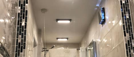 A modern bathroom with a glass shower enclosure, a white towel, and a visible toilet paper dispenser.
