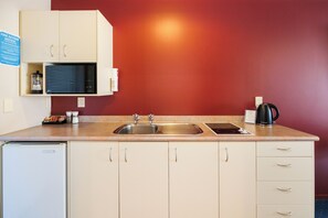 Cozinha com pia, cafeteira e micro-ondas.