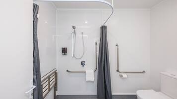 Une salle de bain moderne équipée d’une douche, de toilettes et de barres d’appui.