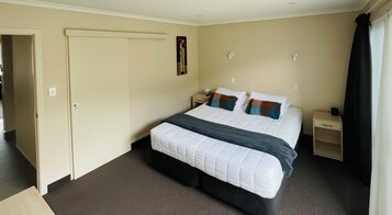 Una habitación de hotel con una cama grande, mesitas de noche, un armario y un cuadro en la pared.