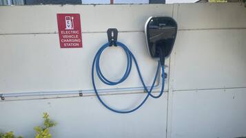 Een laadstation voor elektrische voertuigen met een BMW-stekker en een bord waarop staat dat het voor elektrische auto's is.
