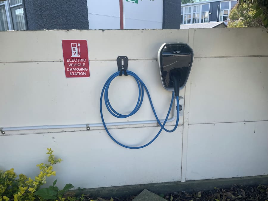 Een laadstation voor elektrische voertuigen met een BMW-stekker en een bord waarop staat dat het voor elektrische auto's is.