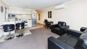 A modern apartment with a kitchen, dining area, and living room. - Kauri Court Motel and Apartments (Palmerston North)