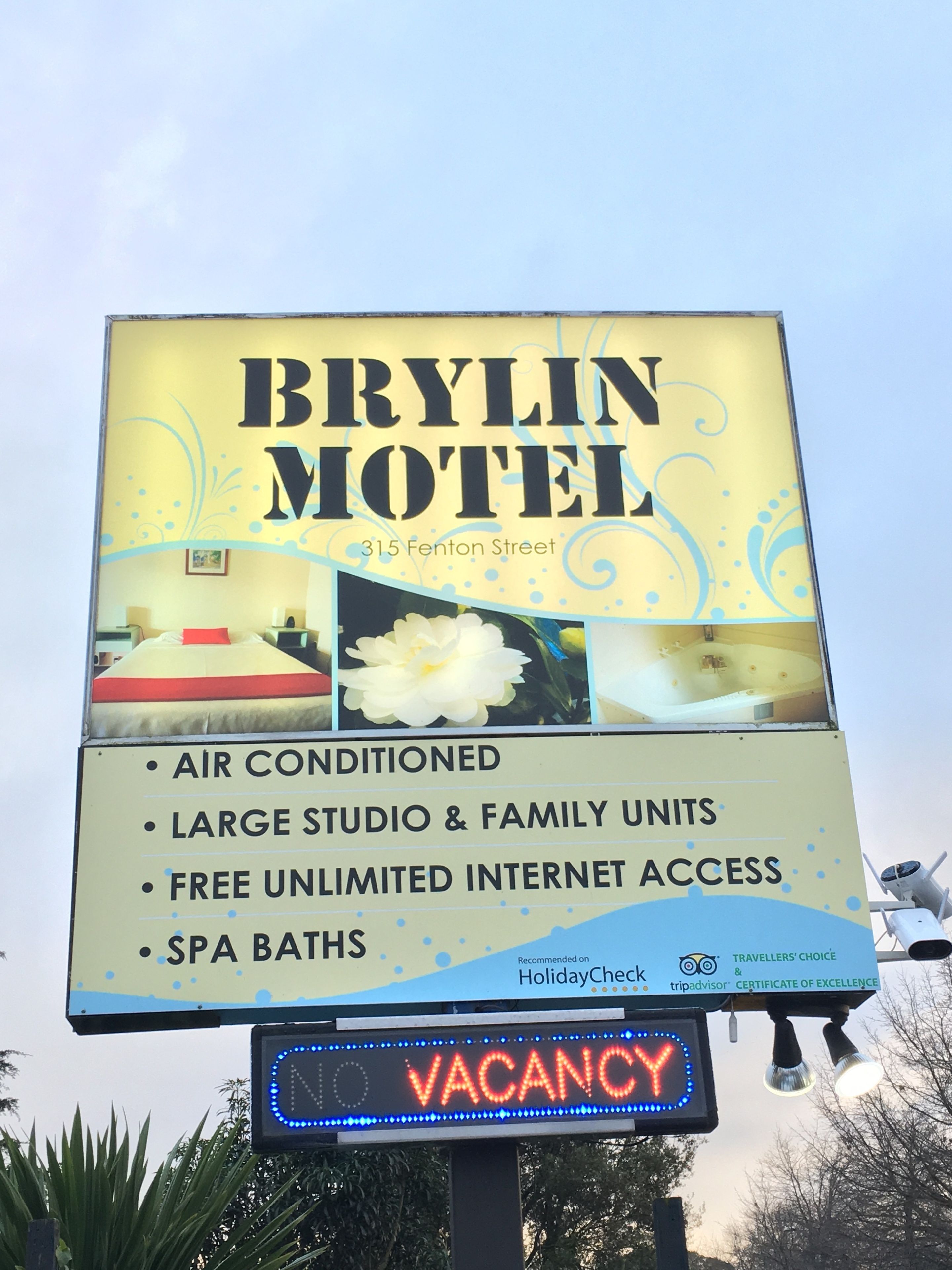 Letrero del Motel Brylin que anuncia habitaciones con aire acondicionado, estudios amplios y unidades familiares, acceso ilimitado gratuito a internet y bañeras spa.