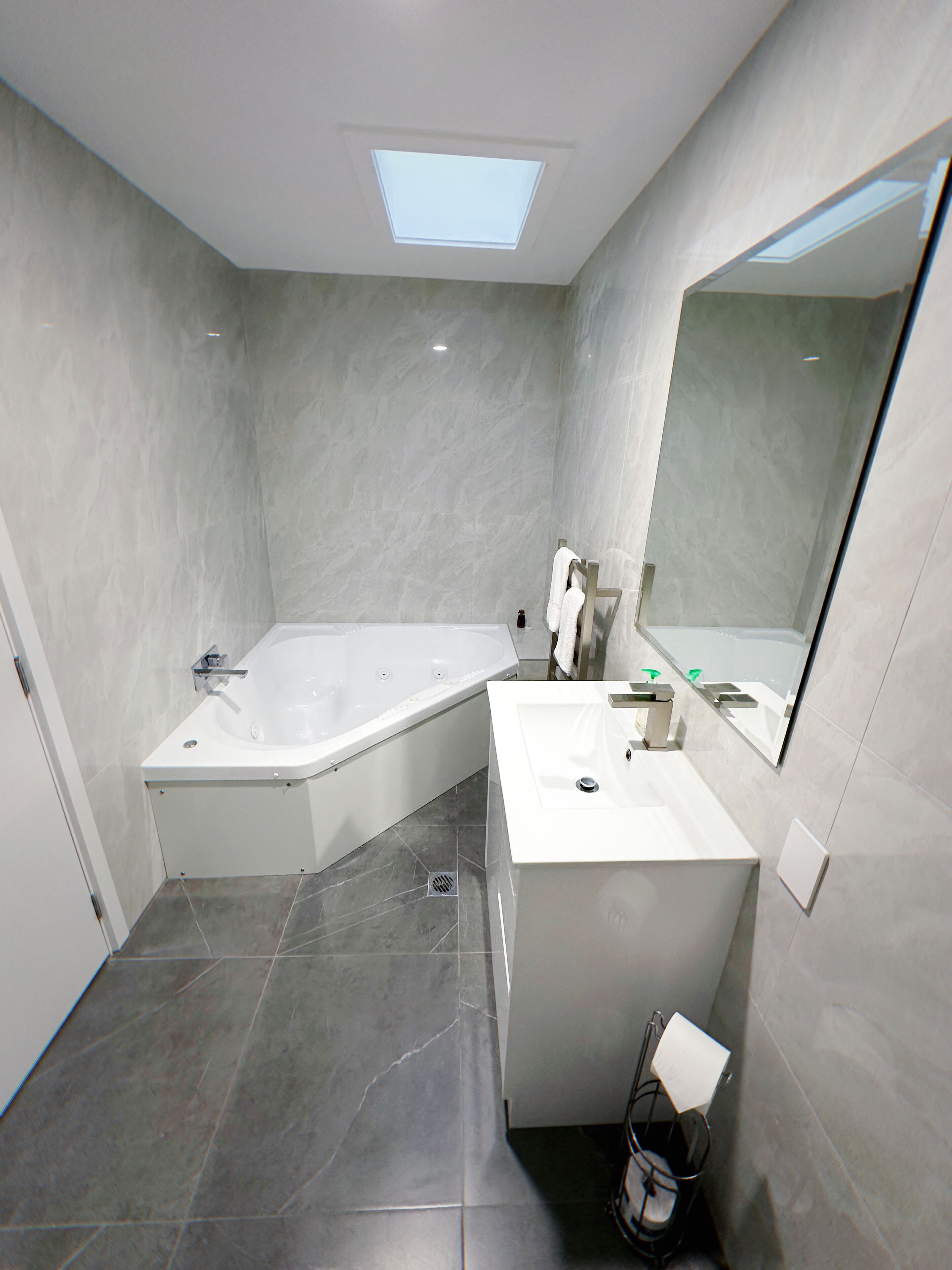 Une salle de bain moderne avec une baignoire sur pieds, un meuble-lavabo avec un miroir et une lucarne.