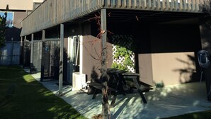 A modern building with a covered outdoor area, a wooden deck, and a clear blue sky. - Brylin Motel (Rotorua)