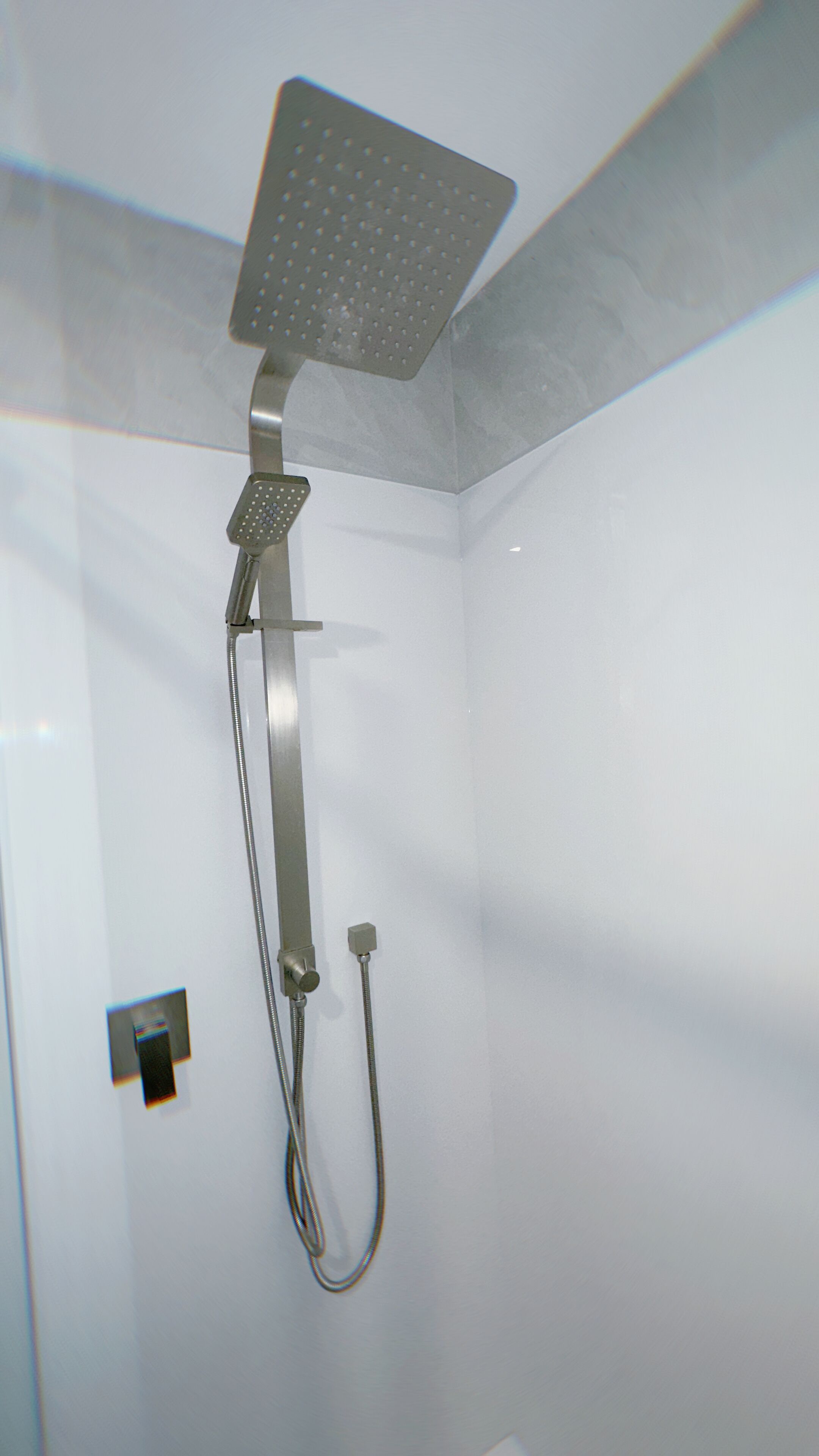 A shower with a handheld showerhead and a handheld shower attachment.