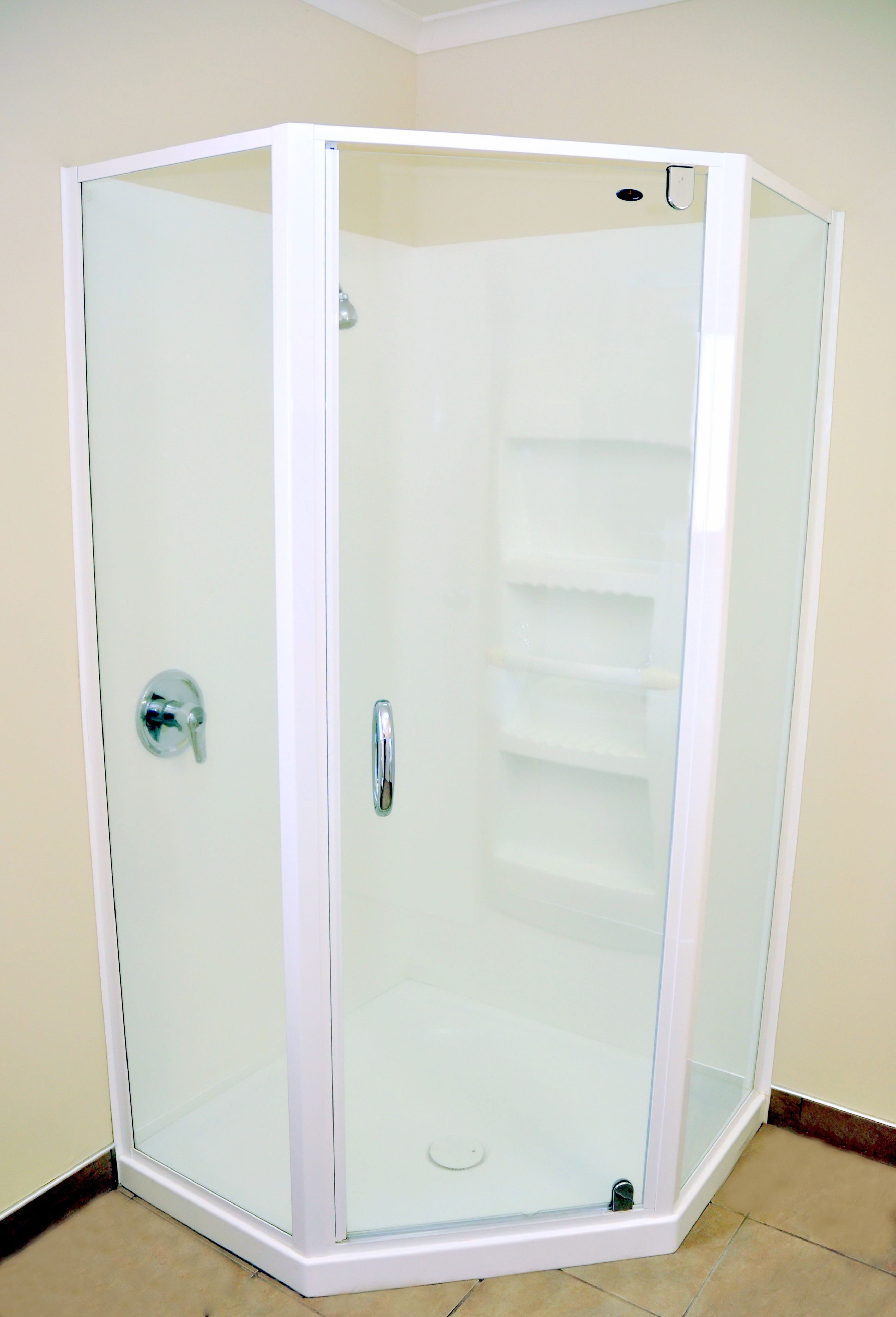 A corner shower enclosure with a glass door and a chrome handle.