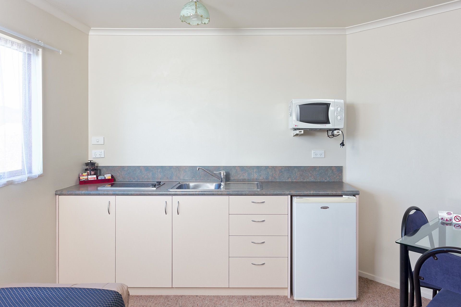 A compact kitchen with a sink, a microwave, and a small refrigerator.
