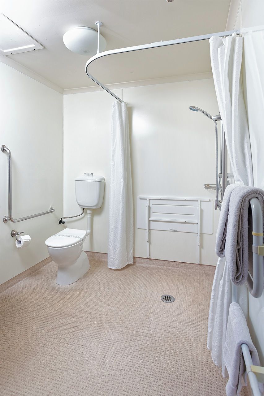 Et moderne badeværelse med toilet, bruser og gelændere.
