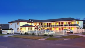 A motel with a two-story structure, multiple parking spaces, and a fenced driveway. - BK's Rotorua Motor Lodge (Rotorua)