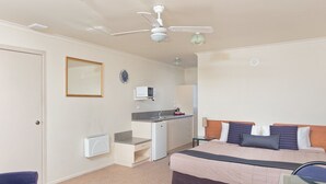 A bedroom with a bed, a desk, a chair, a ceiling fan, and a clock on the wall. - BK's Rotorua Motor Lodge (Rotorua)