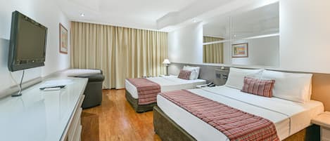 A hotel room with two beds, a TV, a desk, and a mirror.