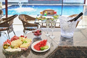 A table with a charcuterie board, a glass of water, a bottle of champagne, and a view of a pool. - Hotel Golden Park Campinas Cambuí By Nacional Inn (Campinas)