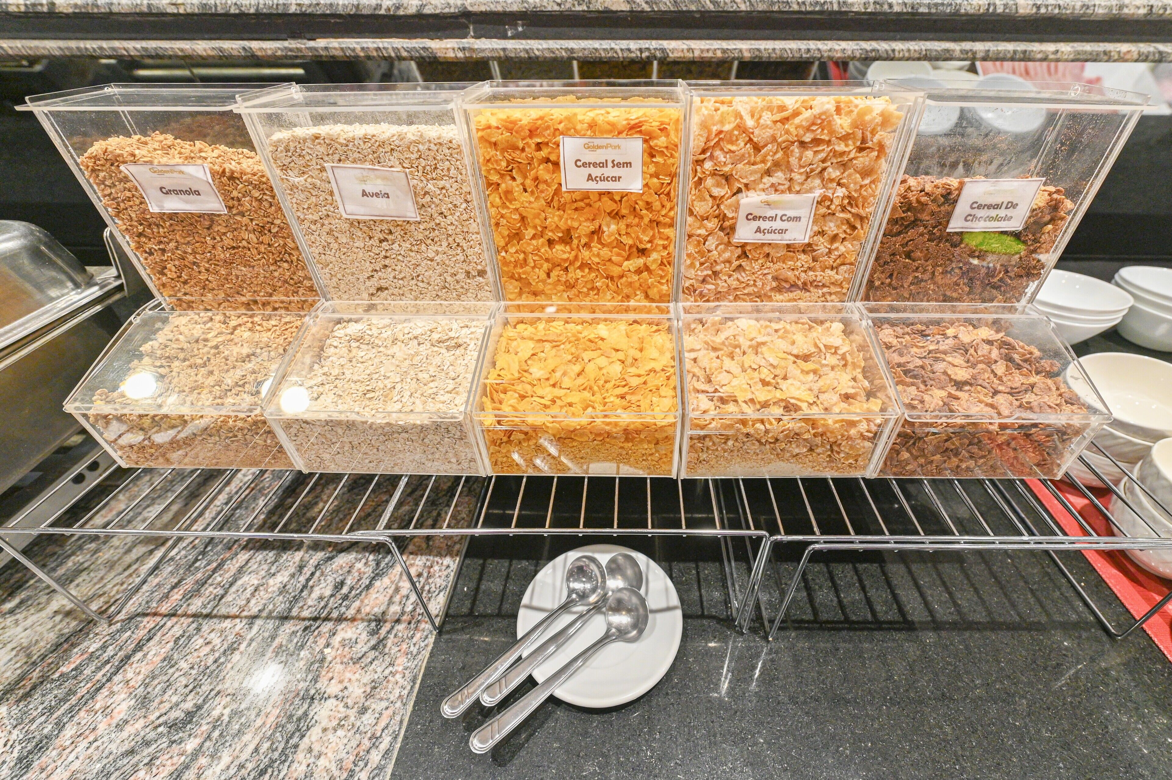 Verschillende soorten ontbijtgranen staan in transparante verpakkingen met etiketten.