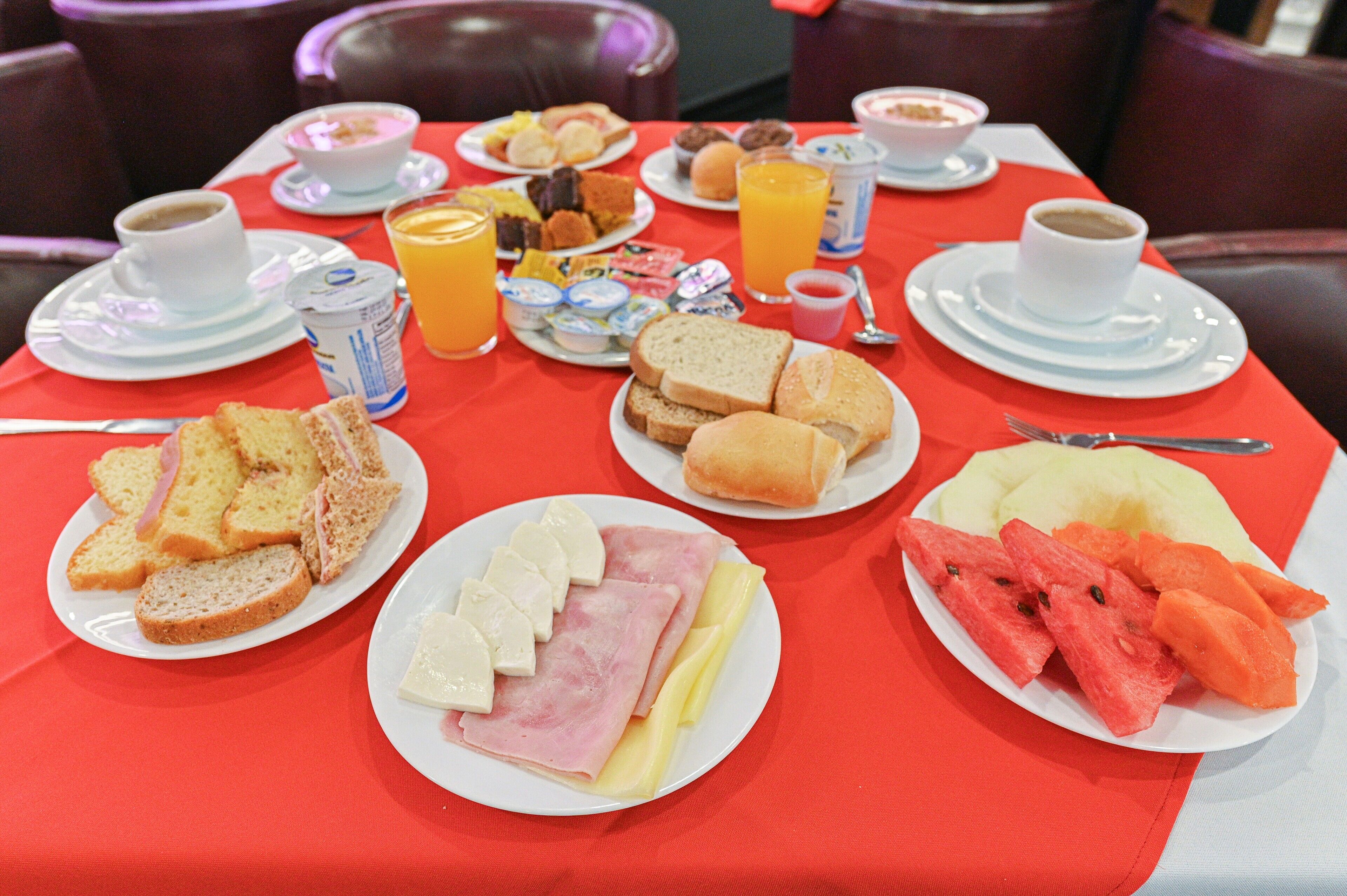 Une table de petit-déjeuner avec des assiettes remplies de nourriture, des tasses de café et du jus d’orange.