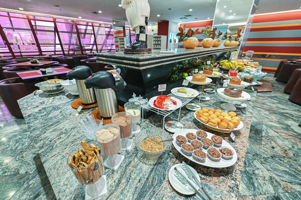 Un bufé con diversos alimentos, entre ellos pasteles, muffins y frutas.