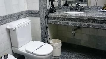Un bagno con un water bianco, un lavabo con piano in granito, uno specchio e un cestino.
