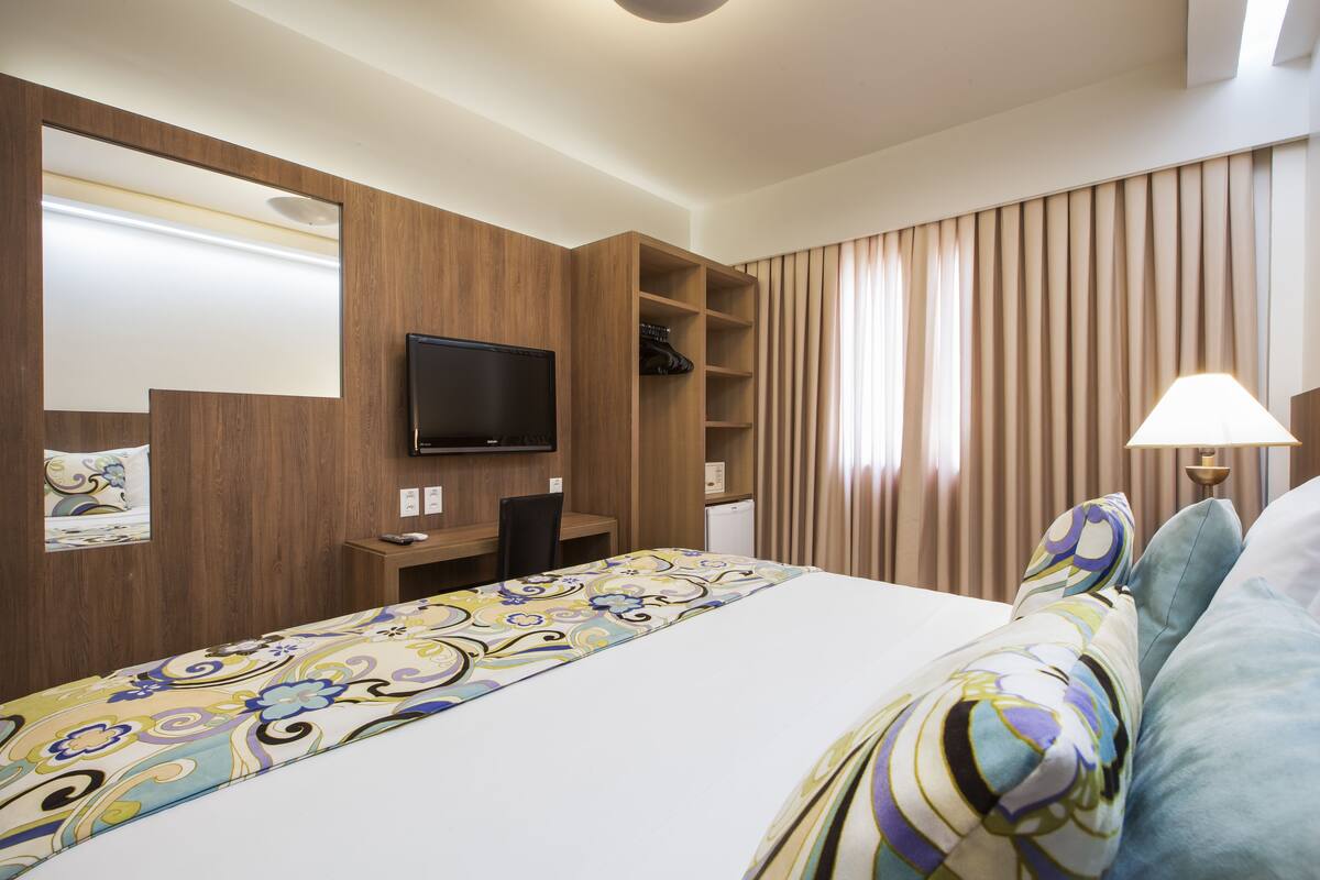 Ein Hotelzimmer mit Bett, Schreibtisch, Fernseher und Kleiderschrank.