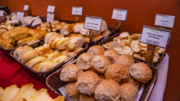 Un buffet proposant différents types de pain et de viennoiseries, notamment du pain à la crème et du pain complet.