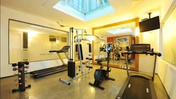 Un gimnasio con tragaluces, equipo de ejercicio y una televisión.