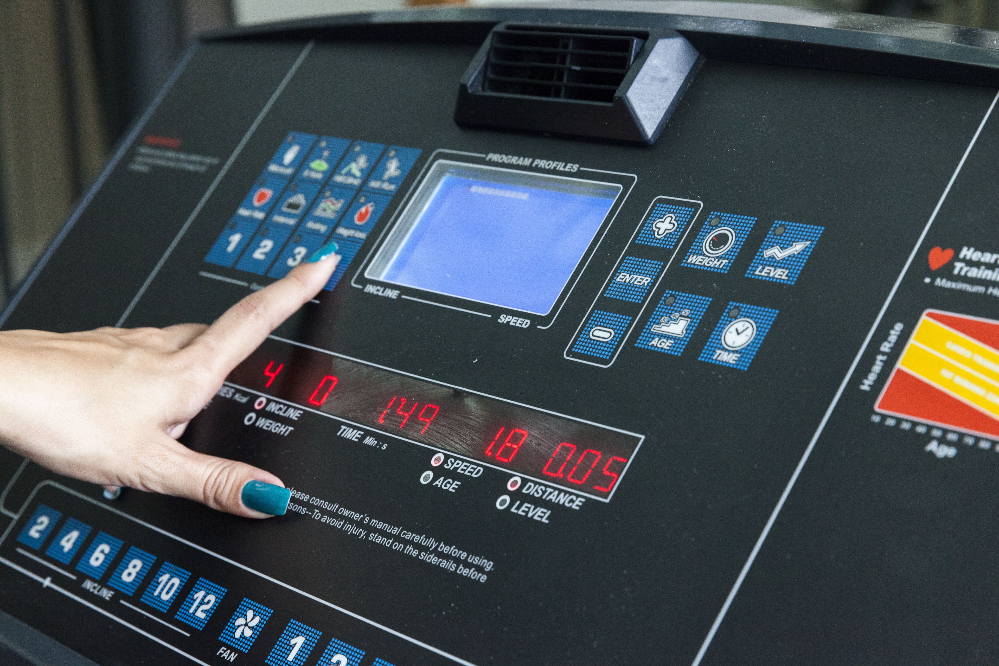 A control panel with digital displays and buttons, including a hand adjusting a knob.