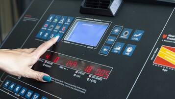 A control panel with digital displays and buttons, including a hand adjusting a knob.