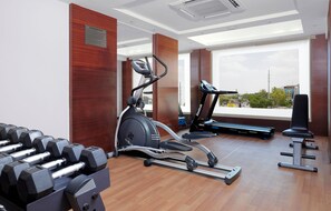 A gym with exercise equipment, large windows, and a view of the city. - Best Western Plus Indore (Indore)