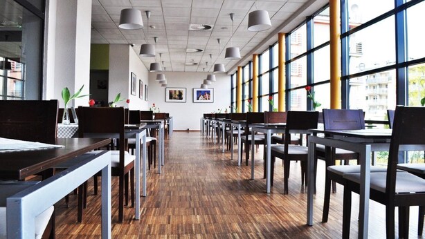 Une bibliothèque spacieuse, avec des rangées de tables et de chaises, de grandes fenêtres et des ventilateurs de plafond.