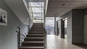 Un intérieur moderne avec un escalier, des rampes en métal et une vue dégagée grâce à de grandes fenêtres.