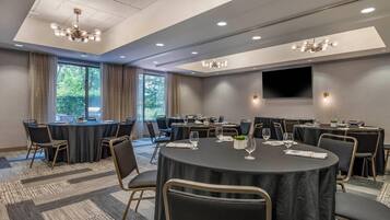 A conference room with round tables, chairs, and a large TV screen.