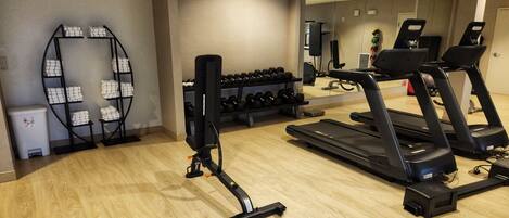 Un gimnasio con cintas de correr, mancuernas y una estructura para sentadillas.