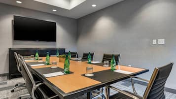 A conference room with a long table, chairs, a flat-screen TV, and water bottles.